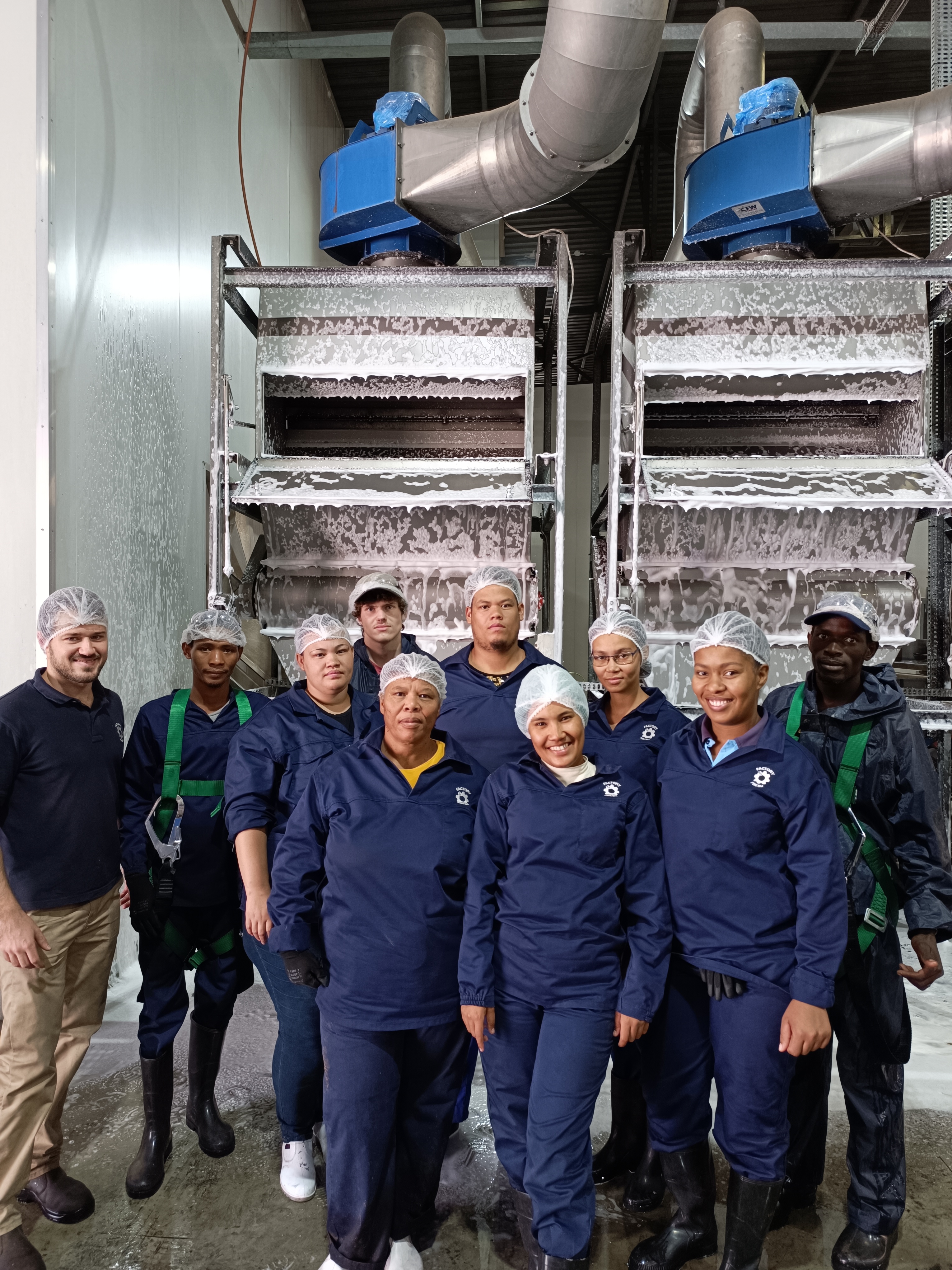 The FactoryFresh team together beside production equipment during a clean