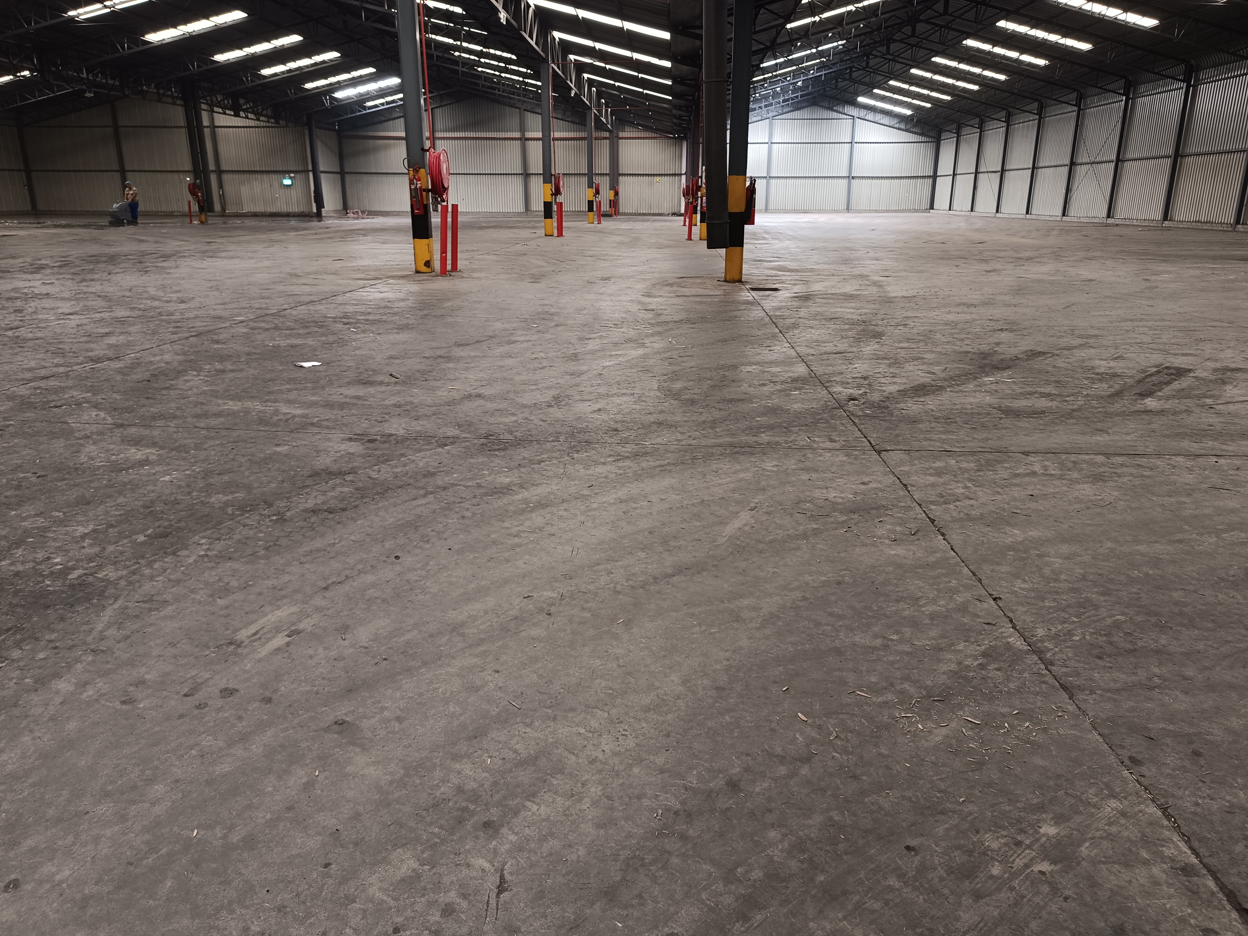 Warehouse floor before cleaning, with visible dirt and loose debris